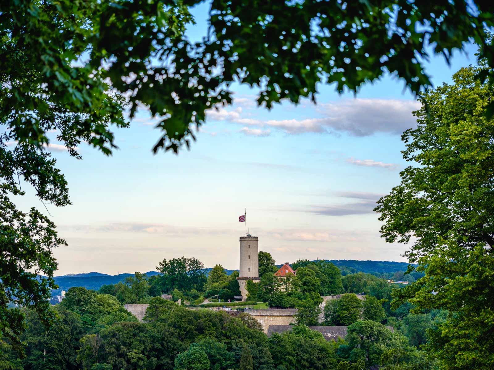 'Sparrenburg' castle, framed by trees, photographed from 'Johannisberg' in June 2020 (Bielefeld, Germany).